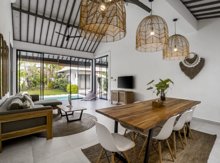 Villa Moju wooden dining table overlooking the living room and big glass doors with pool and garden view