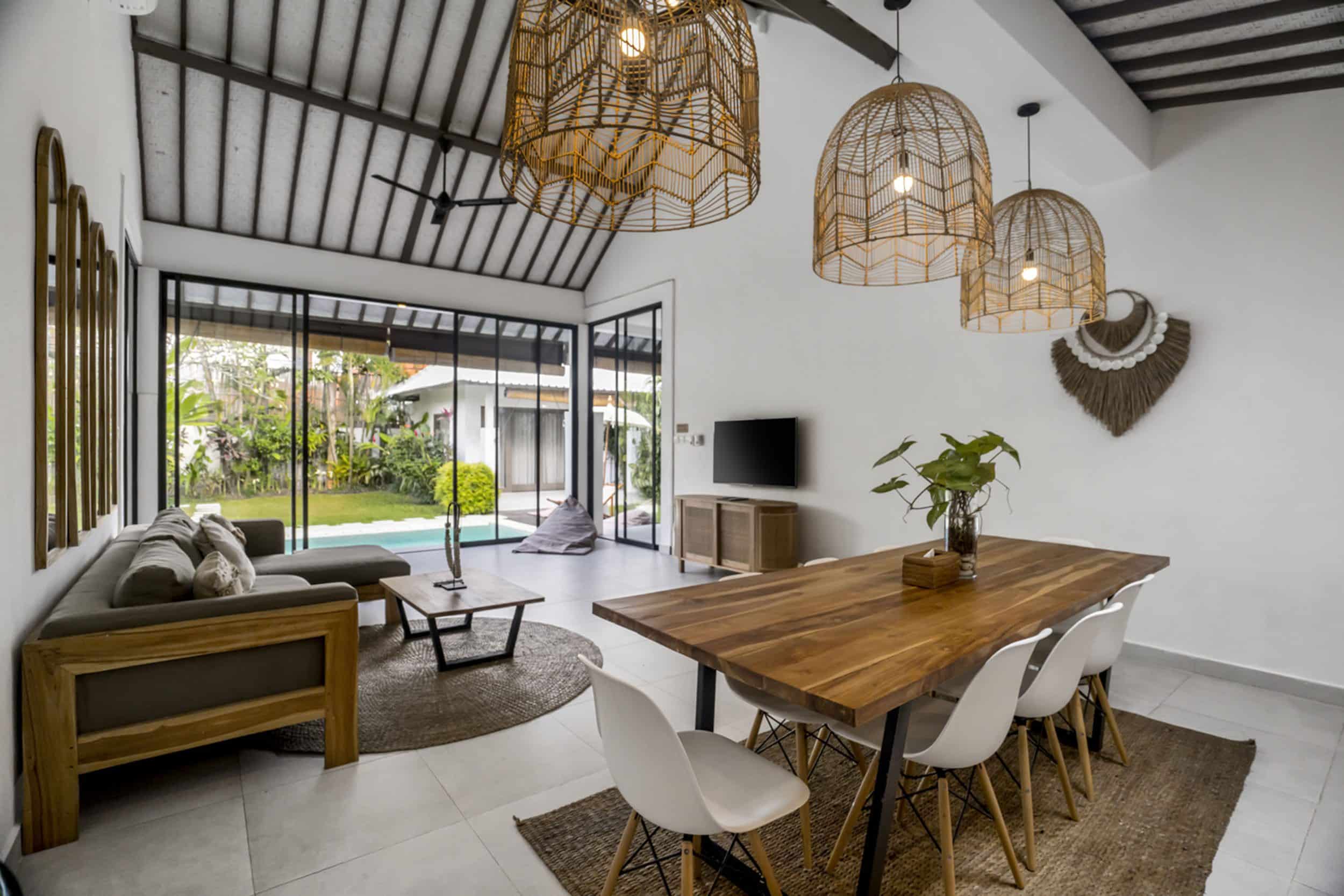 Villa Moju wooden dining table overlooking the living room and big glass doors with pool and garden view