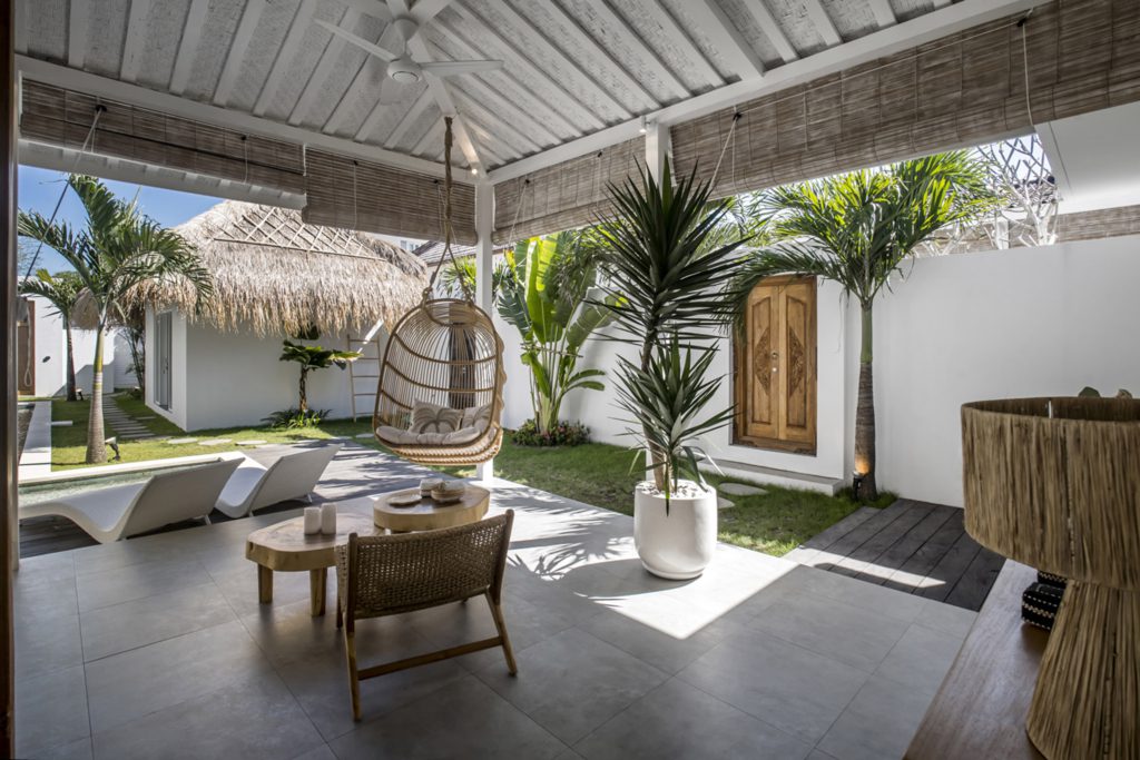 Villa Makena semi-open living room with a rattan hanging swing and a small wooden table with chair