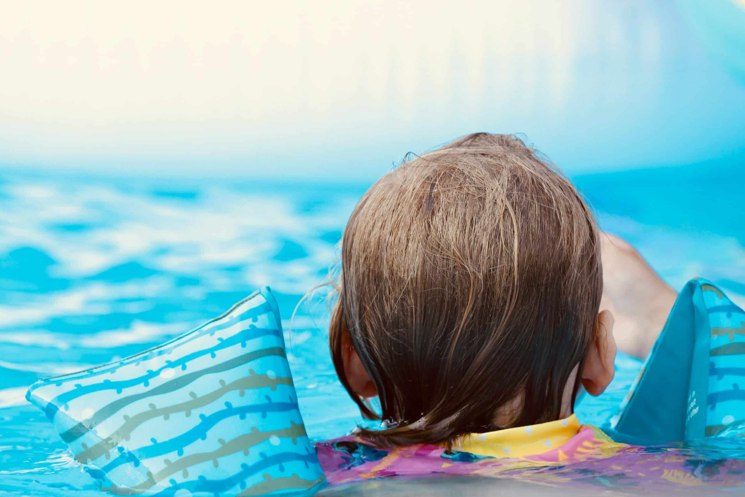 Family friendly activities showing a child swimming in a pool with floaters 