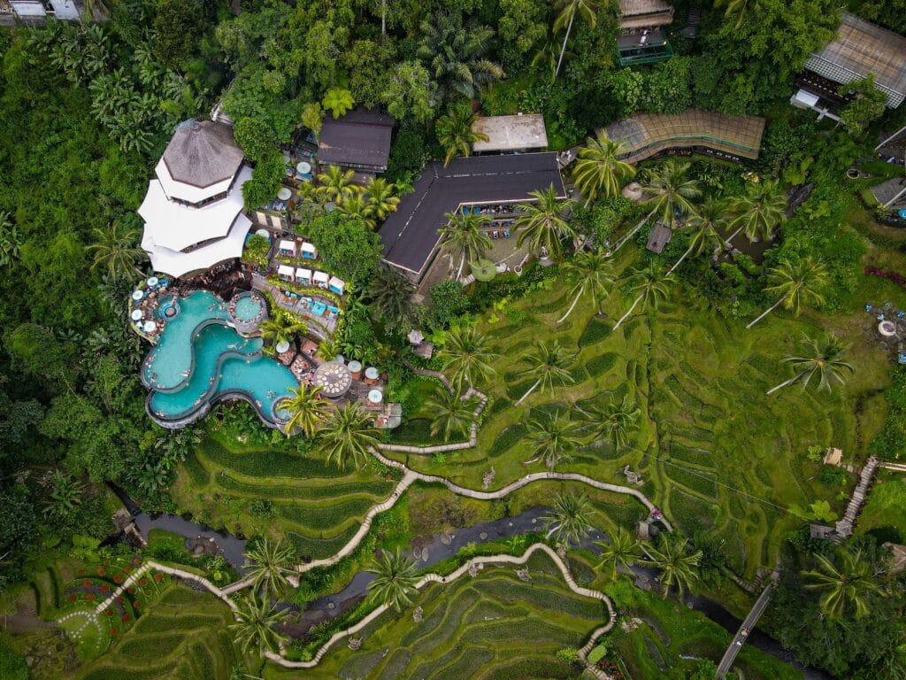 A pool club surrounded by jungle and rice fields seen from a drone-view 