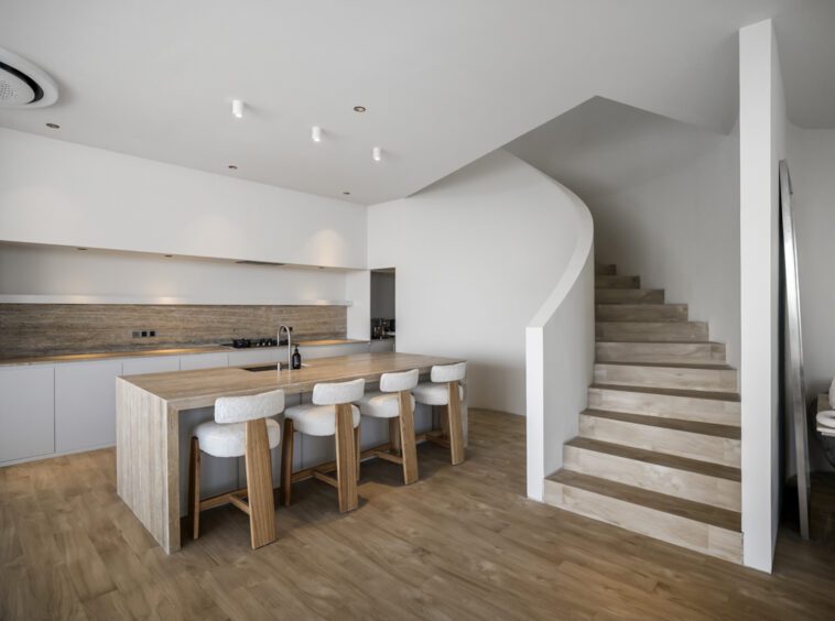 Kitchen area with a bar top and bar stools, situated next to some stairs going upstairs of this private villa in Bingin