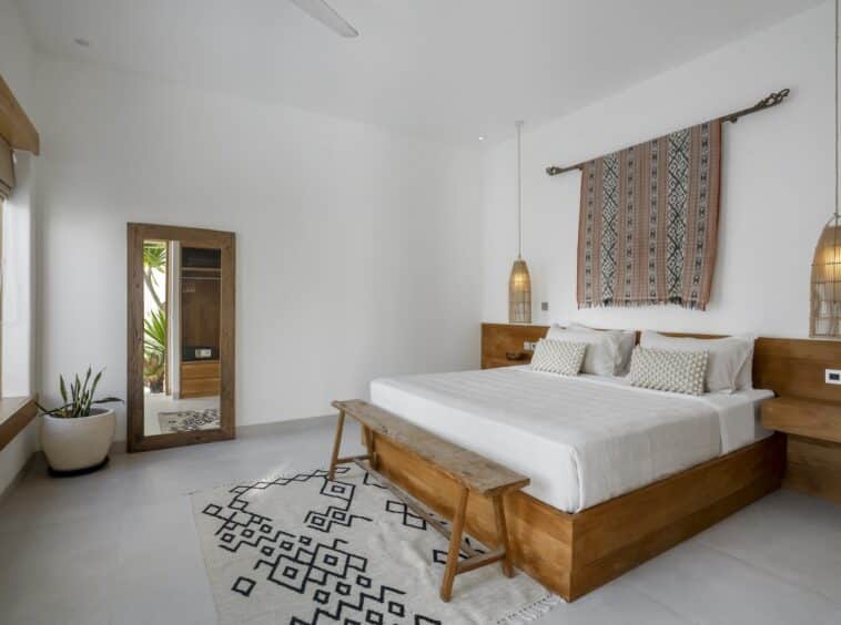 Bedroom with big standing mirror, black and white carpet and wooden furniture