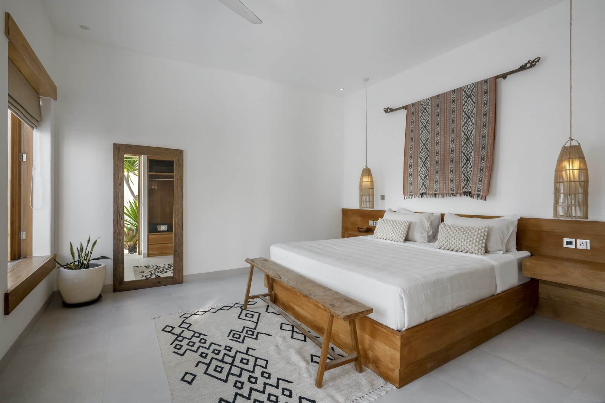 Bedroom with big standing mirror, black and white carpet and wooden furniture