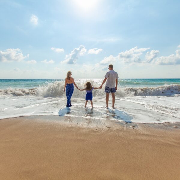 A family doing family friendly activities in Bali by being on the beach and walking towards the waves