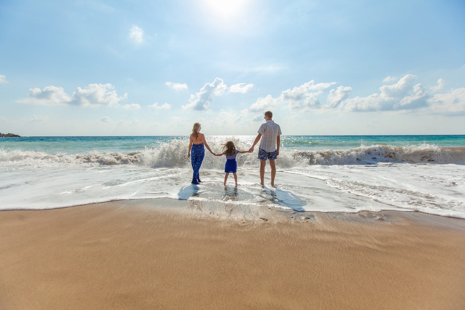 A family doing family friendly activities in Bali by being on the beach and walking towards the waves