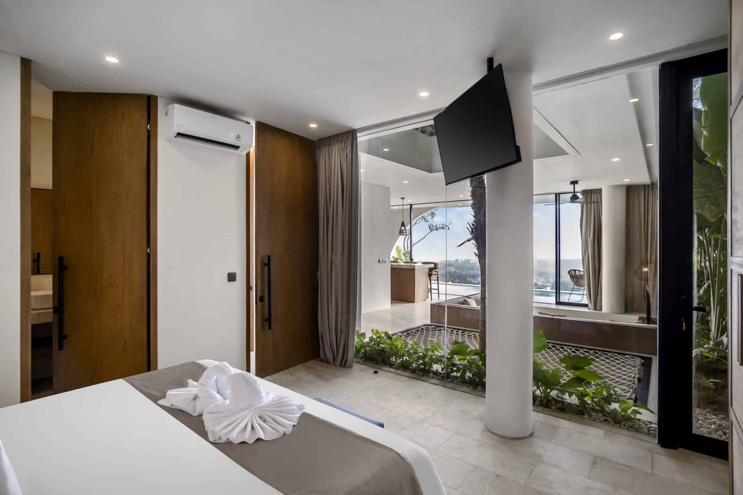 Bedroom in Uluwatu villa with TV and windows towards the living room